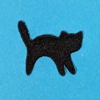 Black cat-shaped fusing glass powder wafer on a blue background