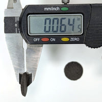 Digital caliper measuring the thickness of a powder wafer reading 0.064in