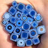 A hand holding a collection of blue and black glass beads or stones.