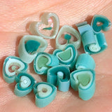 a collection of heart-shaped objects made of a material that appears to be a type of candy or confection. The objects are arranged in a scattered manner on a surface, creating a visually interesting and playful composition.