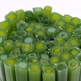 a close-up view of numerous green and yellow glass rods or sticks arranged in a circular pattern.