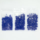 Three clear plastic bags filled with blue beads are arranged in a row.