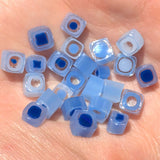 a collection of small, clear blue and white beads or glass pieces scattered on a surface.