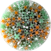The image is a circular arrangement of various colored glass tubes or containers, including shades of green, orange, and white.