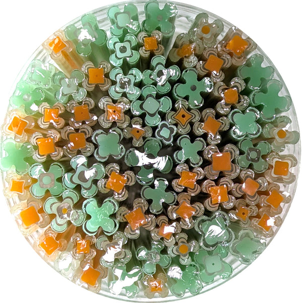 The image is a circular arrangement of various colored glass tubes or containers, including shades of green, orange, and white.