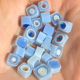A hand holding a collection of small, blue and white quilted beads or beads in a blue and white color scheme.