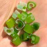 a close-up view of a person's hand holding a collection of green onion slices.