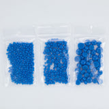 Three clear plastic bags filled with blue beads are arranged in a row.
