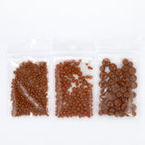 Three clear plastic bags filled with brown objects, possibly beads or nuts, are arranged in a row.