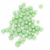 a collection of small, round, green beads scattered across a white background.
