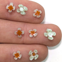 a close-up view of a person's fingers adorned with small, colorful flower-shaped objects made of glass or plastic.