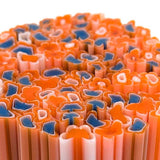 The image is a close-up of a collection of colorful glass tubes or rods, with a pattern of orange and blue shapes.