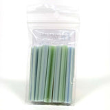 A clear plastic bag containing a collection of green and blue cylindrical objects, which appear to be small tubes or containers.