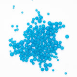 numerous small, round, blue beads scattered across a white background.