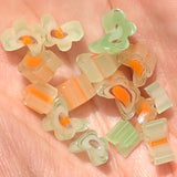 a hand holding a collection of small, colorful beads in various shapes and sizes, including flower-shaped and striped beads.