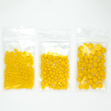 Three plastic bags filled with yellow objects, likely beads or candies, are arranged in a row.