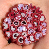 A hand holding a cluster of heart-shaped objects made of red and white materials, possibly candy or other confections.