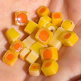 A hand holding a collection of small, colorful candy pieces in shades of yellow and orange.