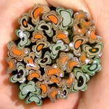 A close-up image of a hand holding a collection of colorful, abstract-shaped objects resembling flowers or leaves.