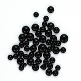 a collection of black spherical objects, possibly beads or spheres, scattered across a white background.