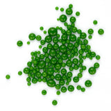 a large number of green beads or spheres, possibly made of glass or plastic, scattered on a white background.
