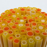 The image is a close-up of a collection of colorful, cylindrical objects, possibly made of glass or plastic, arranged in a circular pattern.