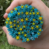 A hand holding a circular arrangement of blue and yellow flower-shaped objects.