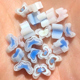 a collection of small, colorful beads or shapes, possibly made of glass or plastic, scattered on a surface.