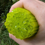 A hand is holding a large, green, leaf-like object that appears to be made of a material that resembles celery or a similar vegetable.
